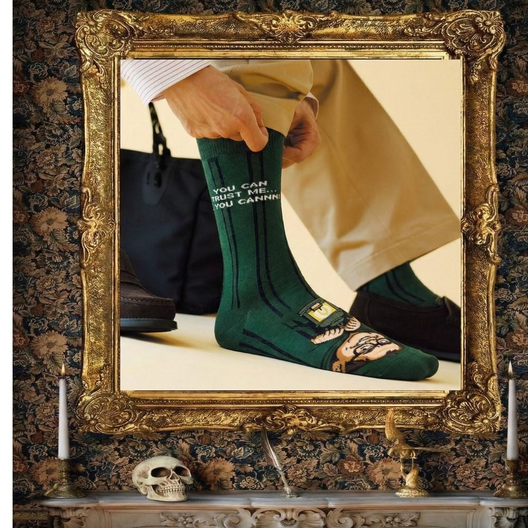 Green Alan Carr Traitors socks worn with cream trousers in a gothic framed scene | Stand4 Socks
