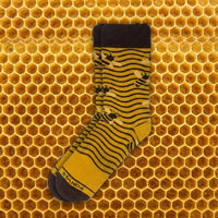 Yellow and black Bee Lines sock displayed on a honeycomb background | Stand4 Socks