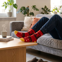 Red Berlin Skyline socks worn while relaxing on a sofa | Stand4 Socks