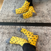 Yellow bee-pattern socks worn on both feet in front of a mirror | Stand4 Socks