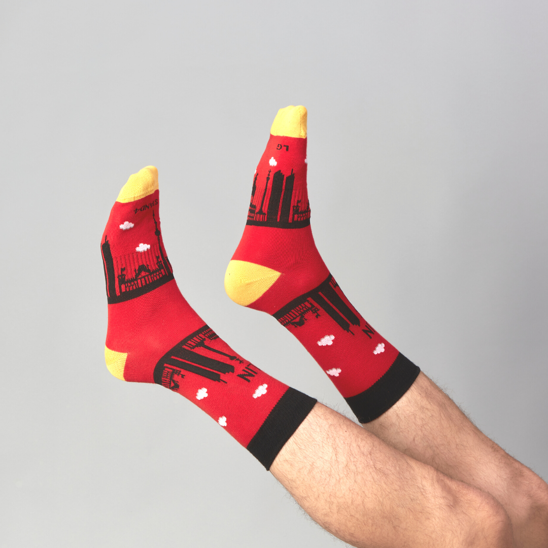 Red Berlin Skyline socks worn on raised feet against a grey background | Stand4 Socks