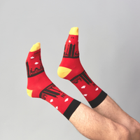 Red Berlin Skyline socks worn on raised feet against a grey background | Stand4 Socks