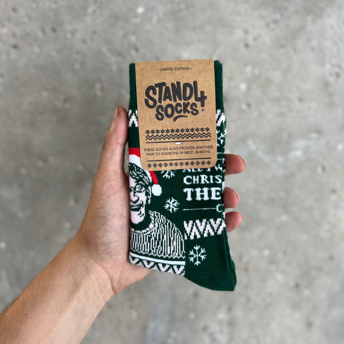Green Christmas Theroux sock in packaging held against a grey background | Stand4 Socks buy one, give one to someone homeless