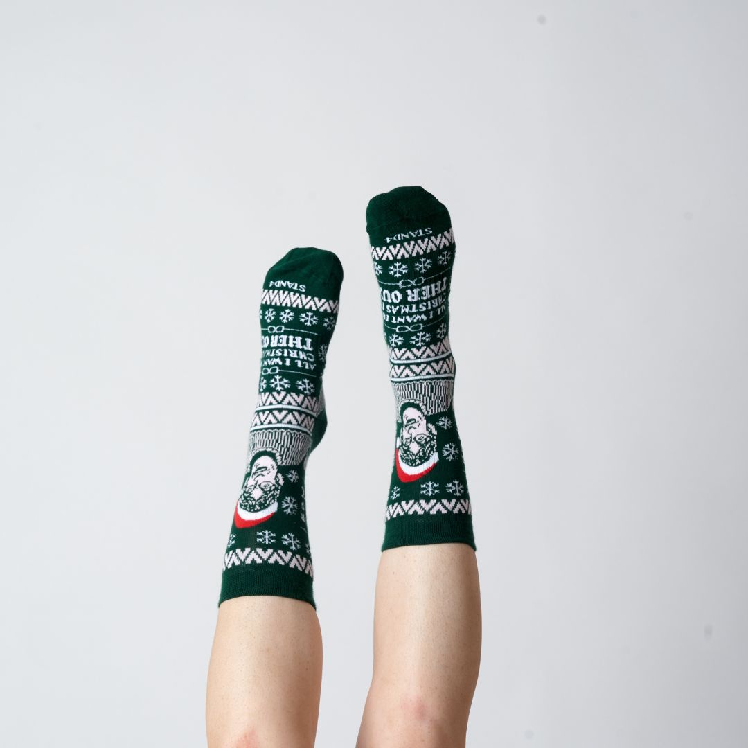 Green Christmas Theroux socks worn on raised feet against a grey background | Stand4 Socks