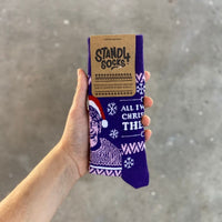 Purple Christmas Theroux sock in packaging held against a grey background | Stand4 Socks